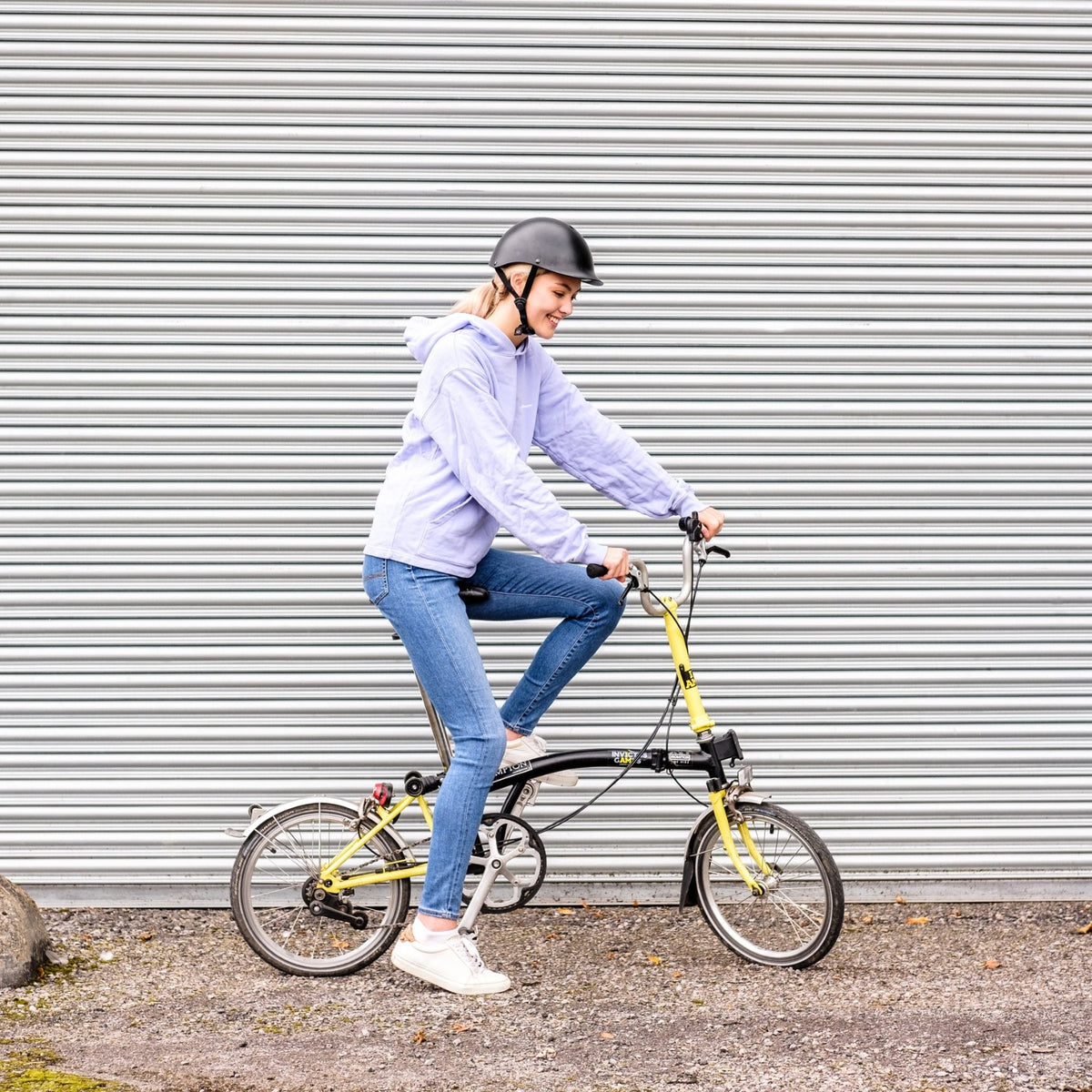 Woman riding a folding bike wearing a Dashel ReCycle Black bike helmet