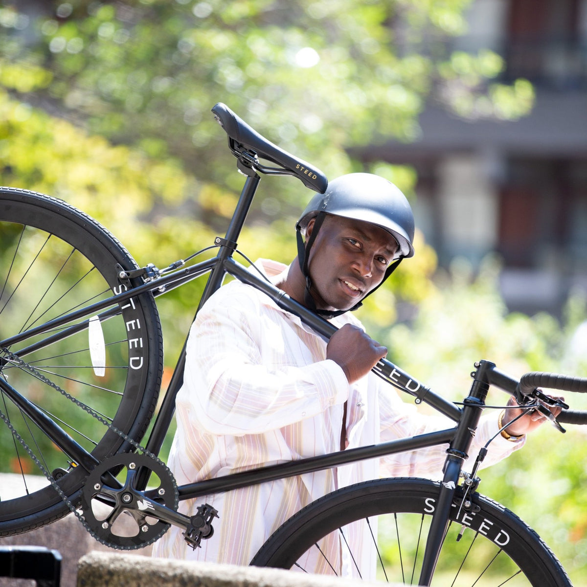 Man carrying a bike on his shoulder wearing a Dashel ReCycle Black bike helmet