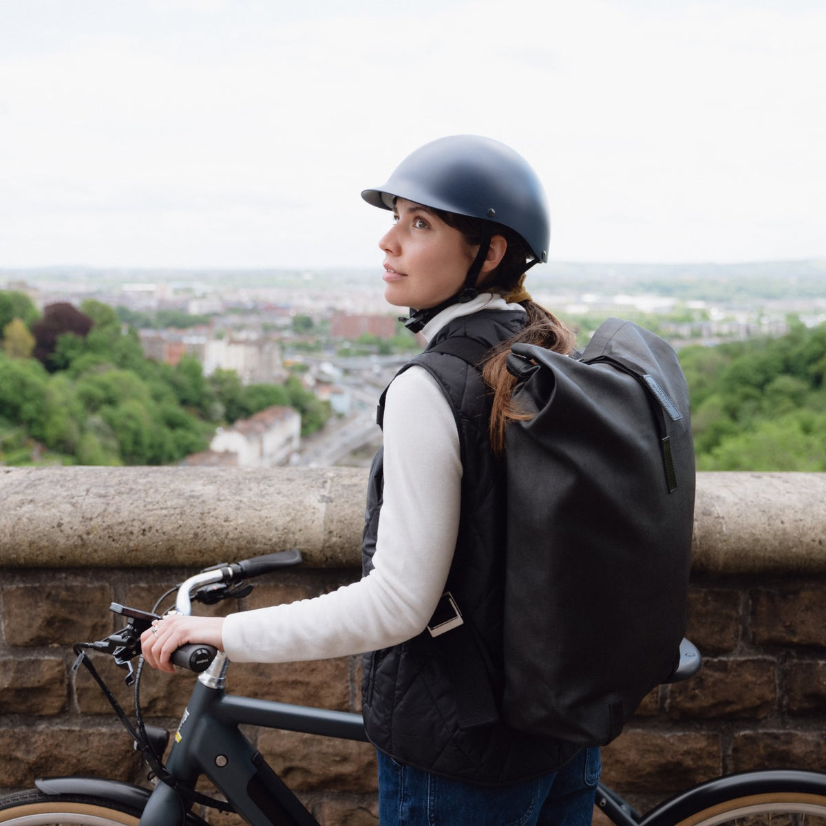 Woman with her bike overlooking the city wearing a Dashel ReCycle Navy Blue bike helmet