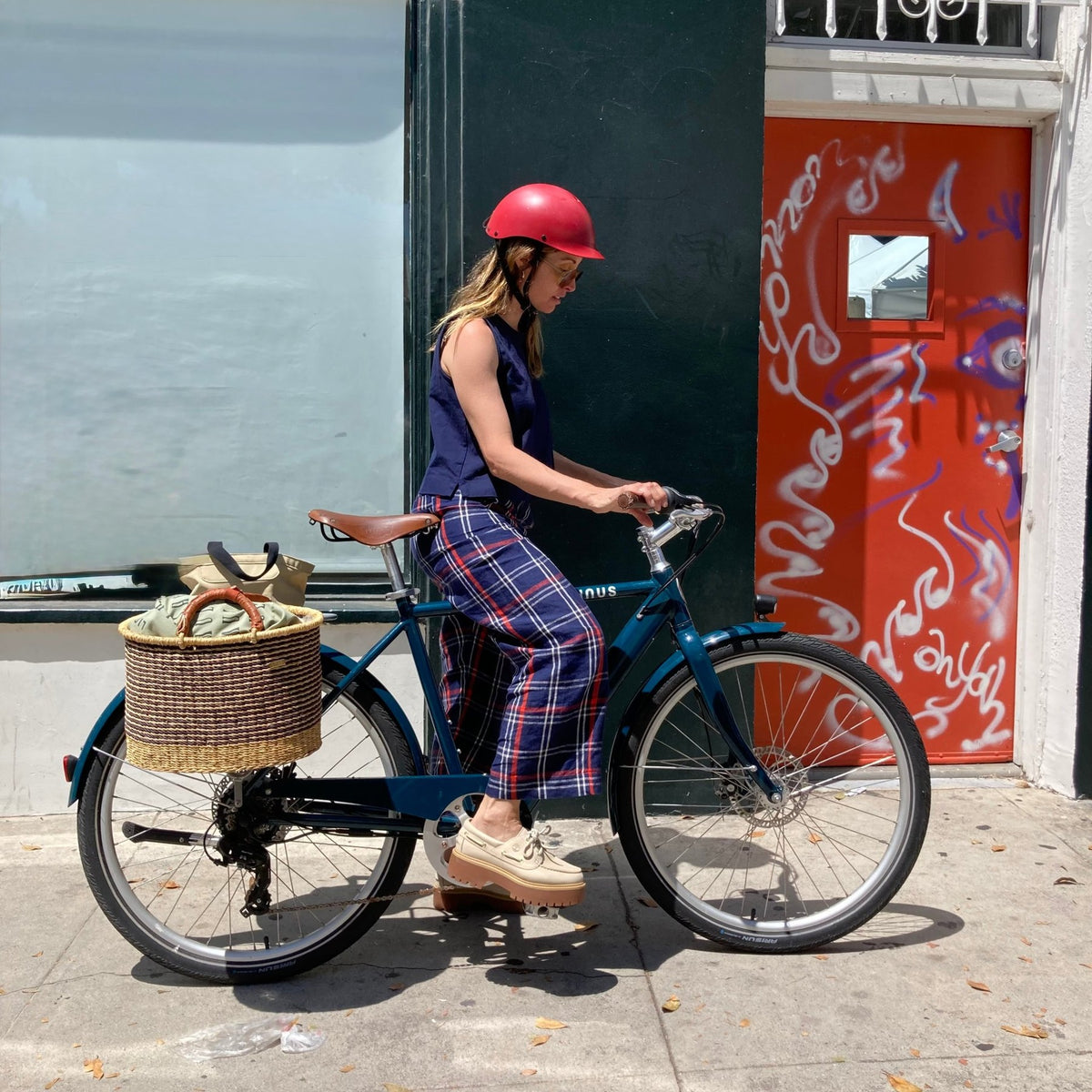Woman on a city bike with a basket wearing a Dashel ReCycle Red bike helmet