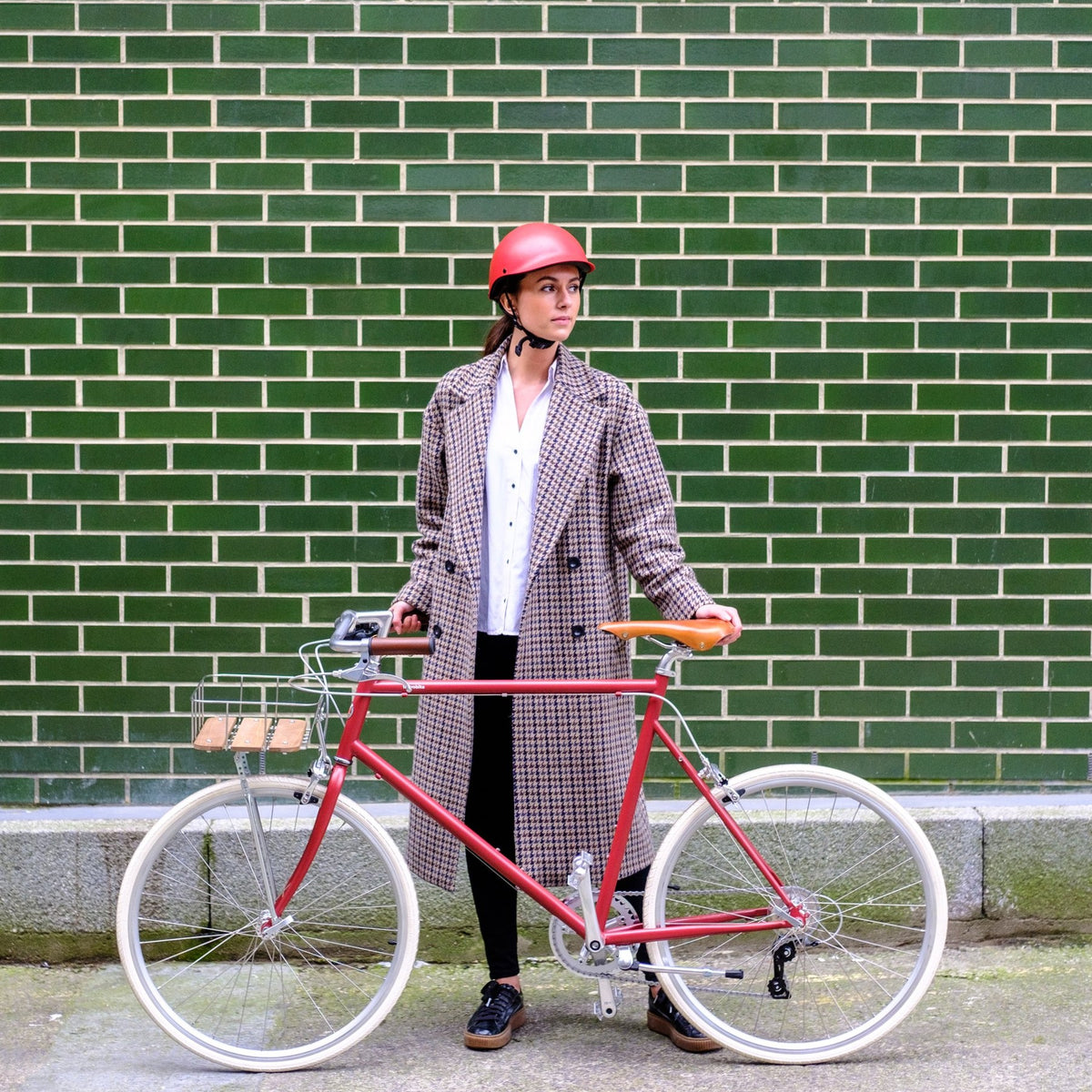 Woman in a long coat standing with her bike wearing a Dashel ReCycle Red bike helmet