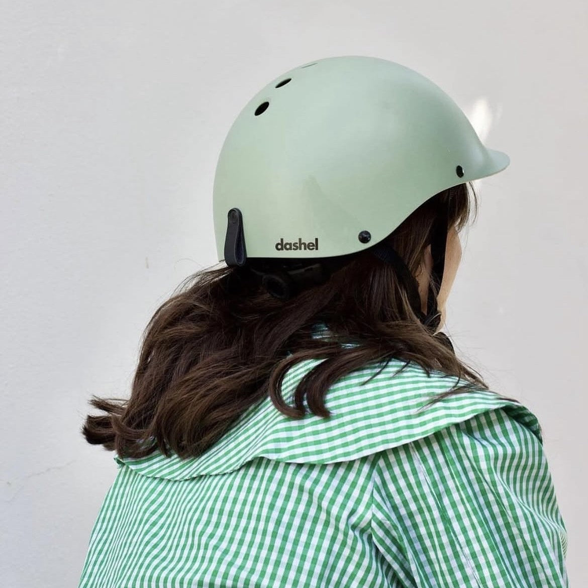 Rear view of a woman wearing a Dashel ReCycle Sage Green bike helmet with Dashel logo