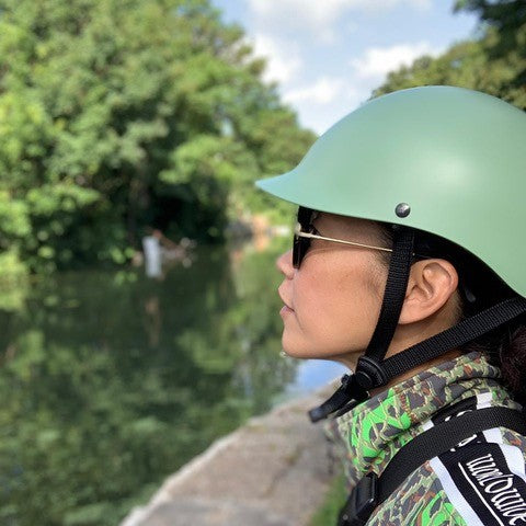 Woman by a river wearing a Dashel ReCycle Sage Green bike helmet