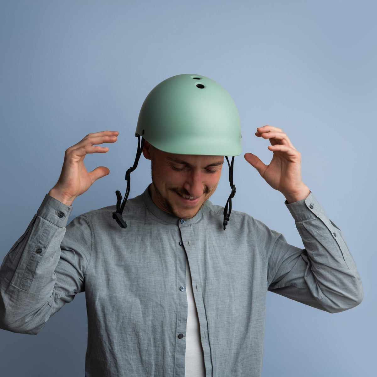 Man putting on a Dashel ReCycle Sage Green bike helmet