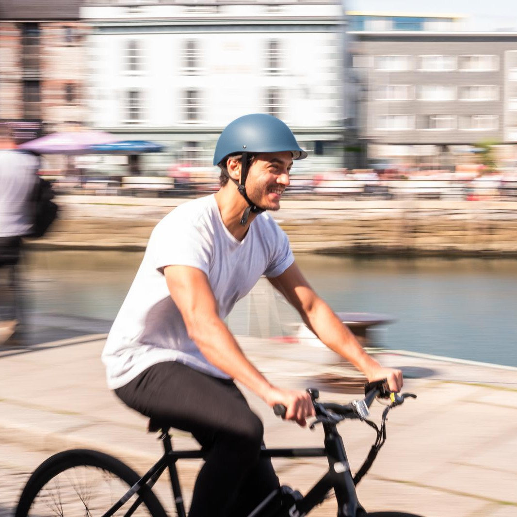 Man riding along a waterfront wearing a Dashel ReCycle Slate Blue bike helmet